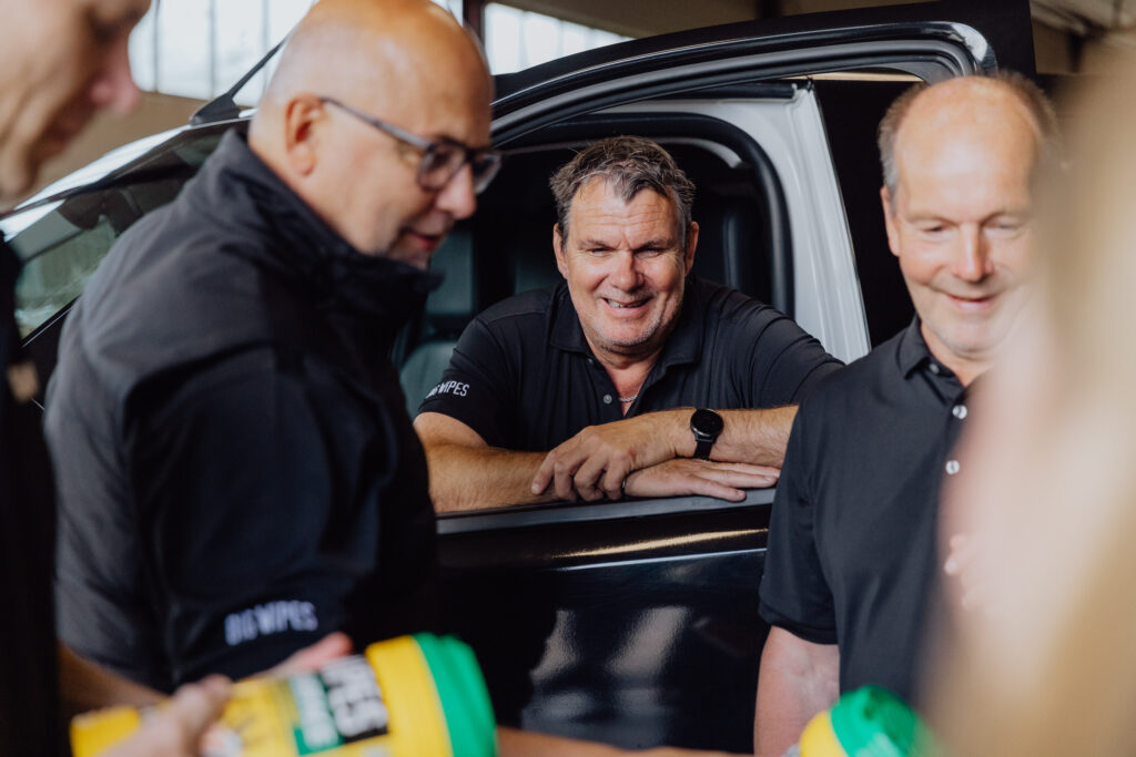 Glada Big Wipes medarbetare vid företagsbil